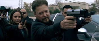 Movie still from “Hostage 911” (2018), directed by Robert Rodriguez – A man holding a gun in front of another man in a car; Close Up shot, Over the shoulder angle