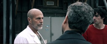 Movie still from “Hostage 911” (2018), directed by Robert Rodriguez – A man standing next to another man in front of an electrical box; Close Up shot, Over the shoulder angle