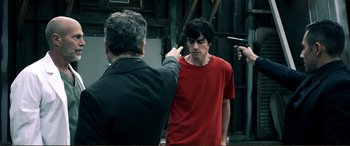 Movie still from “Hostage 911” (2018), directed by Robert Rodriguez – A man pointing at a man in a red shirt; Medium shot, Over the shoulder angle