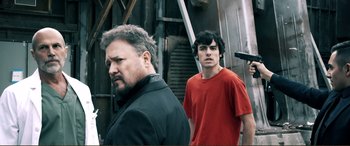 Movie still from “Hostage 911” (2018), directed by Robert Rodriguez – A man standing next to a young man in front of a building; Medium shot, Low angle