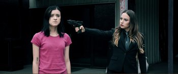 Movie still from “Hostage 911” (2018), directed by Robert Rodriguez – A woman holding a gun pointed at another woman; Medium shot, Over the shoulder angle