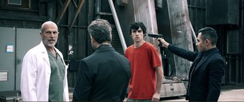Movie still from “Hostage 911” (2018), directed by Robert Rodriguez – A man holding a gun in front of two other men; Medium shot, Over the shoulder angle