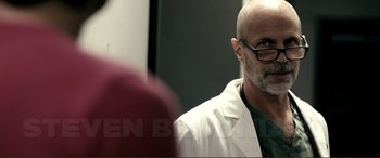 Movie still from “Hostage 911” (2018), directed by Robert Rodriguez – A man in a white lab coat is looking into the mirror; Close Up shot, Over the shoulder angle
