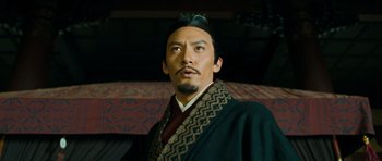 Movie still from “Red Cliff” (2008), directed by John Woo – A man with a beard wearing a hat and a black robe; Close Up shot, Low angle
