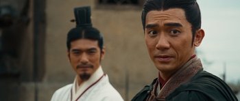 Movie still from “Red Cliff” (2008), directed by John Woo – Two asian men standing next to each other in front of a building; Close Up shot, Over the shoulder angle