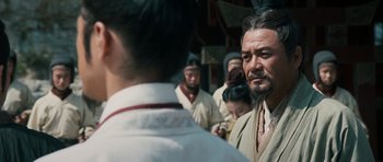 Movie still from “Red Cliff” (2008), directed by John Woo – A man with a long beard standing in front of a group of people; Close Up shot, Over the shoulder angle