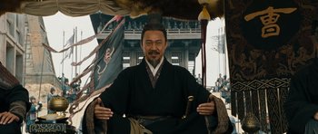 Movie still from “Red Cliff” (2008), directed by John Woo – A man sitting in a chair wearing a black robe; Medium shot, Low angle
