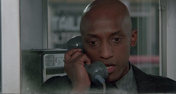 Movie still from “Red Heat” (1988), directed by Walter Hill – A man talking on a phone while sitting in a chair; Close Up shot, Low angle