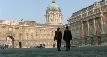 Movie still from “Red Heat” (1988), directed by Walter Hill – Two men are walking in front of an old building; Extreme Wide shot, Low angle