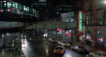 Movie still from “Red Heat” (1988), directed by Walter Hill – Cars are parked on the side of the road at night; Extreme Wide shot, High angle