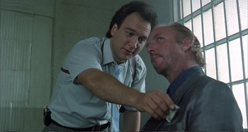 Movie still from “Red Heat” (1988), directed by Walter Hill – A man is giving a man money in a room; Close Up shot, Low angle