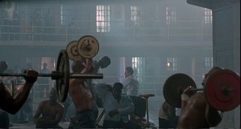 Movie still from “Red Heat” (1988), directed by Walter Hill – A group of people in a room with barbells in their hands; Wide shot, High angle