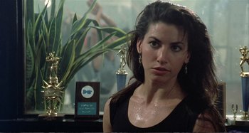 Movie still from “Red Heat” (1988), directed by Walter Hill – A woman in a black shirt is in front of a trophy; Close Up shot, Over the shoulder angle