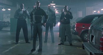 Movie still from “Red Heat” (1988), directed by Walter Hill – A group of men standing next to each other in a parking garage; Wide shot, Low angle