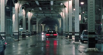 Movie still from “Red Heat” (1988), directed by Walter Hill – A car driving down a street under a bridge; Extreme Wide shot, High angle