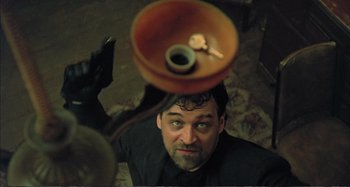 Movie still from “Red Heat” (1988), directed by Walter Hill – A man is sitting on the floor with a bowl on top of his head; Close Up shot, Overhead angle