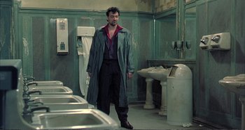 Movie still from “Red Heat” (1988), directed by Walter Hill – A man standing in front of urinals in a bathroom; Medium shot, Low angle