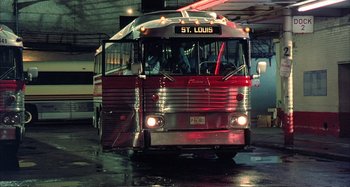 Movie still from “Red Heat” (1988), directed by Walter Hill – A red and silver bus parked in a parking lot; Wide shot, Low angle