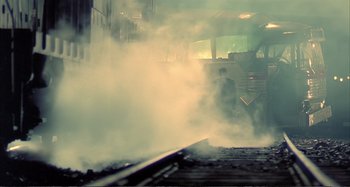 Movie still from “Red Heat” (1988), directed by Walter Hill – A man standing next to train tracks with steam coming out of it; Wide shot, Low angle