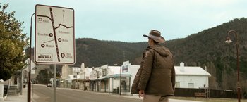 Movie still from “Red Hill” (2010), directed by Patrick Hughes – A man in a hat is standing on the side of the road; Wide shot, Low angle