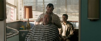 Movie still from “Red Hill” (2010), directed by Patrick Hughes – A man getting his hair cut by another man; Medium shot, Over the shoulder angle