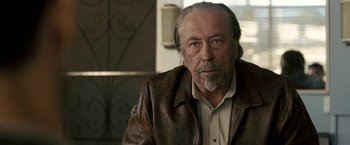 Movie still from “Red Hill” (2010), directed by Patrick Hughes – An older man wearing a leather jacket and looking at the camera; Close Up shot, Over the shoulder angle