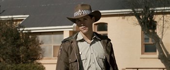 Movie still from “Red Hill” (2010), directed by Patrick Hughes – A man wearing a brown hat and a brown jacket; Medium shot, Over the shoulder angle