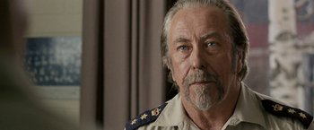 Movie still from “Red Hill” (2010), directed by Patrick Hughes – An older man wearing a military uniform looking at the camera; Close Up shot, Over the shoulder angle