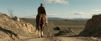 Movie still from “Red Hill” (2010), directed by Patrick Hughes – A man riding a horse down a dirt road; Extreme Wide shot, Low angle