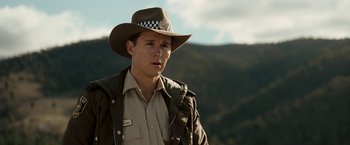 Movie still from “Red Hill” (2010), directed by Patrick Hughes – A man wearing a hat and a jacket standing in front of a mountain range; Close Up shot, Over the shoulder angle