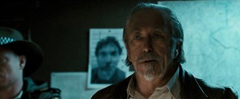 Movie still from “Red Hill” (2010), directed by Patrick Hughes – An older man standing in front of a picture of himself; Close Up shot, Over the shoulder angle