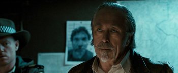 Movie still from “Red Hill” (2010), directed by Patrick Hughes – An older man standing in front of a picture of himself; Close Up shot, Low angle