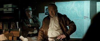 Movie still from “Red Hill” (2010), directed by Patrick Hughes – A man in a brown leather jacket standing next to another man in a brown leather jacket; Medium shot, Over the shoulder angle