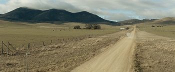Movie still from “Red Hill” (2010), directed by Patrick Hughes – A dirt road running through the middle of a field; Extreme Wide shot, High angle