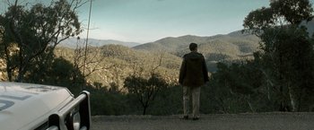 Movie still from “Red Hill” (2010), directed by Patrick Hughes – A man standing on top of a hill looking out at the mountains; Extreme Wide shot, High angle
