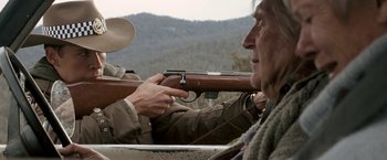 Movie still from “Red Hill” (2010), directed by Patrick Hughes – An old man holding a rifle and pointing at something; Medium shot, Over the shoulder angle