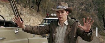 Movie still from “Red Hill” (2010), directed by Patrick Hughes – A man wearing a hat standing in front of a truck; Close Up shot, Over the shoulder angle