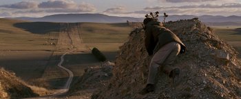 Movie still from “Red Hill” (2010), directed by Patrick Hughes – A man is climbing a hill in the desert; Extreme Wide shot, High angle