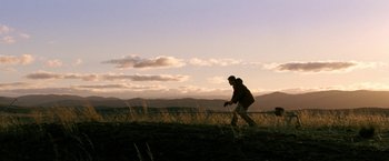 Movie still from “Red Hill” (2010), directed by Patrick Hughes – A man standing on top of a grass covered field; Extreme Wide shot, Low angle