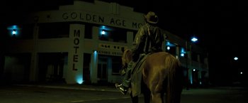 Movie still from “Red Hill” (2010), directed by Patrick Hughes – A man riding a horse down a street at night; Wide shot, Low angle