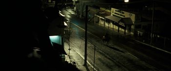 Movie still from “Red Hill” (2010), directed by Patrick Hughes – A person riding a horse down a street at night; Extreme Wide shot, High angle