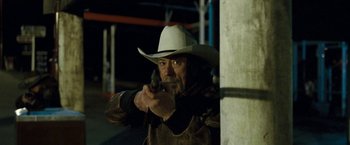 Movie still from “Red Hill” (2010), directed by Patrick Hughes – A man in a white cowboy hat holding a gun; Medium shot, Over the shoulder angle