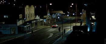 Movie still from “Red Hill” (2010), directed by Patrick Hughes – A white car driving down a street at night; Extreme Wide shot, High angle