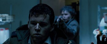 Movie still from “Red Hill” (2010), directed by Patrick Hughes – A man with blood on his face and another man with a gun in the background; Close Up shot, Over the shoulder angle