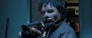 Movie still from “Red Hill” (2010), directed by Patrick Hughes – A person holding a gun in a room; Close Up shot, Low angle