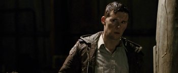 Movie still from “Red Hill” (2010), directed by Patrick Hughes – A man in a brown jacket is looking at the camera; Close Up shot, Over the shoulder angle