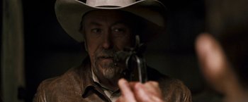Movie still from “Red Hill” (2010), directed by Patrick Hughes – A man in a cowboy hat holding a gun; Close Up shot, Over the shoulder angle