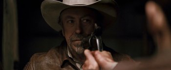 Movie still from “Red Hill” (2010), directed by Patrick Hughes – A man in a cowboy hat is holding a gun; Close Up shot, Over the shoulder angle