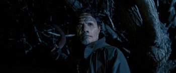 Movie still from “Red Hill” (2010), directed by Patrick Hughes – A man with a beard and a curly mustache in a dark forest; Close Up shot, Low angle