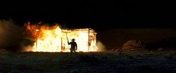 Movie still from “Red Hill” (2010), directed by Patrick Hughes – A man holding a gun standing in front of a burning building; Wide shot, Low angle